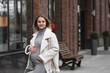 © Юлия Клюева - A beautiful young pregnant woman holding her tummy in an autumn park. The expectant mother walks in the fresh air on an autumn day and enjoys the wonderful moments of pregnancy in nature.