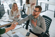 © standret - Man is sitting and making handshake with woman. Successful team are working together in the office