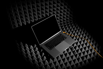 Wall Mural - Laptop mockup template on a black soundproof foam background with deep shadows, real photo. Blank isolated to place your design. 