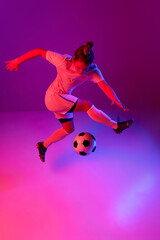 Wall Mural - Dribbling. Young professional female football, soccer player in motion, training, playing over gradient pink background in neon light