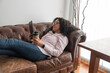 © ADDICTIVE STOCK - Woman drinking coffee and using tablet on sofa