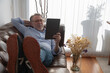 © ADDICTIVE STOCK - Positive man using tablet on sofa