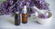 A bottle of essential oil with fresh blooming lavender twigs