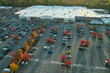 Aerial view of large parking lot in front of rgocery store with many parked colorful cars. Carpark at supercenter shopping mall with lines and markings for vehicle places and directions