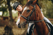 © sergo321 - A young woman jockey lies on her horse and hugs her.