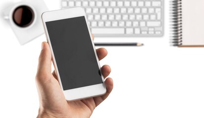 Poster - Hand holding a modern smartphone on office desk background.