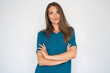 © Mangostar - Portrait of beautiful young woman with crossed arms. Female Caucasian model with brown hair and grey eyes in turquoise T-shirt and casual jeans smiling crossing arms on chest. Lifestyle concept