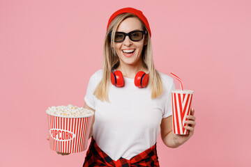 Wall Mural - Young smiling happy fun cheeerful satisfied cool woman in 3d glasses watch movie film hold bucket of popcorn cup of soda pop in cinema isolated on plain pastel light pink background studio portrait.