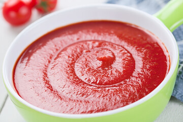 Wall Mural - Fresh homemade tomato soup in green bowl, photographed on white wood (Very Shallow Depth of Field, Focus one third into the image)
