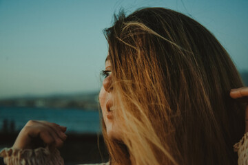 Wall Mural - Girl on the beach with long hair, summer mood. Sunset, woman in a beautiful dress on vacation, and accessories, portrait, wind in her hair.