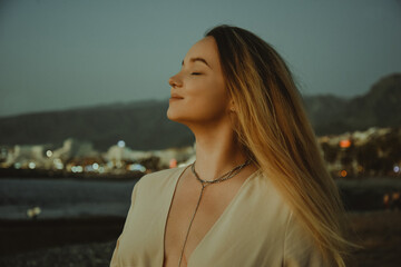 Wall Mural - Gorgeous girl in a dress and jewelry on the background of the sunset on the background of the sea, a woman with long hair on vacation portrait, palm trees.