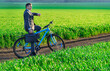 a businessman rides a bicycle with a briefcase and checks his wrist watch on a green grassy field, dressed in a business suit, beautiful nature in spring, freelance business concept