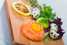 Tartar Of 200 Gramm Salmon With Balsamic, Greens, Black Pepper, Olive Oil, Lemon, Quail Egg On Wooden Desk..
