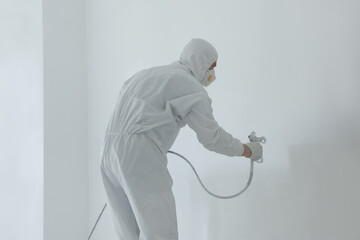 Wall Mural - Decorator painting white wall with spray indoors