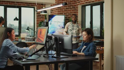 Smiling coworker talking to 3D developer about digital art production, explaining graphics developing skills. Creative agency diverse employees brainstorming ideas about engineering work.