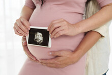 Pregnant Couple Holding Ultrasound Scan Photo On Belly