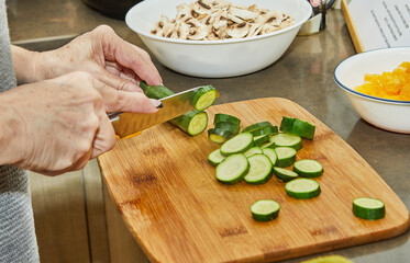 Sticker - Chef cuts zucchini for salad on wooden board in the kitchen