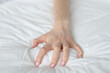 © H_Ko - Strongly clenched female hand on sheet on bed