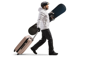 Sticker - Full length profile shot of a young man holding a snowboard and pulling a suitcase