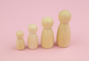 Growing up females concept. Different size female wooden people figures on pink background.