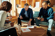 © Flamingo Images - Smiling businesspeople going over paperwork during an office meeting