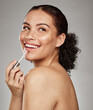 © K.A./peopleimages.com - Woman, lipstick and beauty makeup cosmetics for skincare or glow against a grey studio background. Happy female smiling with teeth in satisfaction for lip, mouth and applying cosmetic treatment