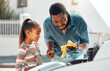 © K.A./peopleimages.com - Oil change, father and child learning about car for mechanic repair of family vehicle outdoor. Black man teaching daughter while bonding and working on engine for transport, safety and insurance