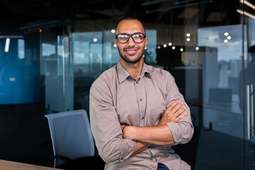 Portrait of hispanic successful businessman, successful man in shirt looking at camera with crossed arms, worker inside office near window.