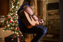 Boy Playing Guitar In Front Of Christmas Tree
