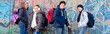© Solid photos - Four smiling teenagers standing in front of the wall after going to school in autumn
