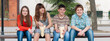 © Solid photos - Four smiling teenagers sitting on the bench in spring and  eating popcorn