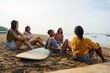 © Jovo Jovanovic/Stocksy - Group of friends with surfboard relaxing on sea shore at beach