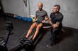 © Bisual Studio/Stocksy - Trainer controlling sportsman on rowing machine