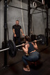 © Bisual Studio/Stocksy - Sportswoman exercising with barbell near trainer
