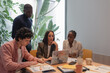 © Milles Studio/Stocksy - Multiracial businesspeople brainstorming at table