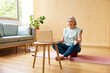© ALTO IMAGES/Stocksy - Senior woman having online yoga lesson