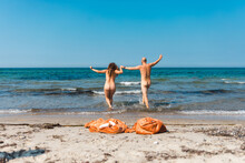 Naked Couple Running For A Swim Together Clothes Left On The Shore