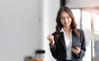 Image of a young Asian businesswoman standing using mobile phone at the office.