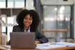 Portrait of attractive african american businesswoman working with laptop and documents on office desk.