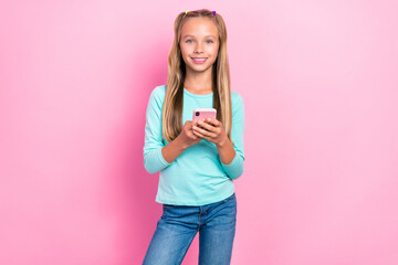 Wall Mural - Photo of cheerful cute schoolkid toothy smile hold use telephone isolated on pink color background