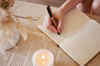 © M Bam/peopleimages.com - Hand, candle and woman writing in journal with top view for calm, peace mindset and relax morning routine in home. Hands, notebook and diary planning goals, idea vision or creative writer lifestyle
