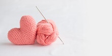 Crocheted Amigurumi Pink Heart With Crochet Hook And Skein Of Yarn On A White Background. Valentine's Day Banner