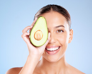 Wall Mural - Woman, studio portrait and avocado skincare with smile, health or wellness by blue background. Model, fruit and face with natural cosmetic beauty, glow or healthy aesthetic with self care by backdrop