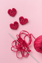 Crocheted Amigurumi Purple Red Burgundy Heart With Crochet Hook On A Pink Background. Valentine's Day