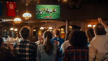 Group Of American Football Fans Watching A Live Match Broadcast In A Sports Pub On TV. People Cheering, Supporting Their Team. Crowd Goes Ecstatic When Team Scores A Goal And Wins The Championship.