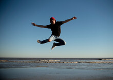 Happy Teenage Boy Jumping On The Beaches Of Galveston, Texas.