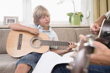 Woman With Her Son Playing Guitar In Living Room, Bavaria, Germany