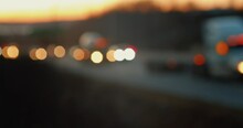 Bokeh Blurred Car Traffic On A Freeway In The Evening Twilight, Driving Part Of A Suburban Highway With Trucks And Cars In The Evening. Blur Abstract Traffic Background Of Busy Highway.