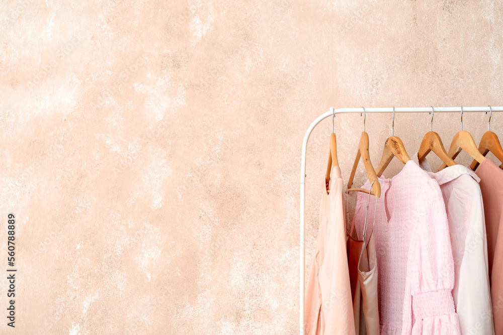 Rack with stylish female clothes near pink wall