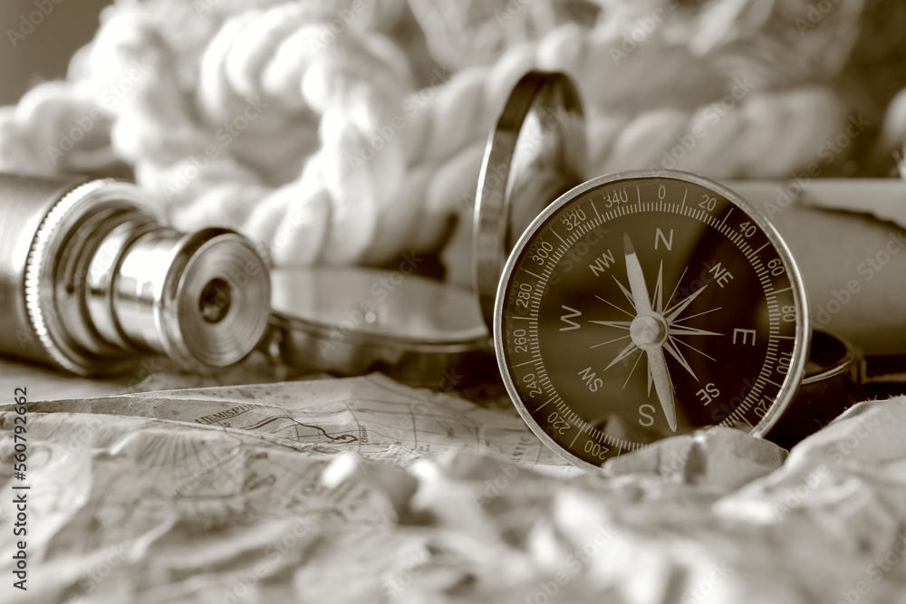 Vintage compass on crumpled world map, closeup